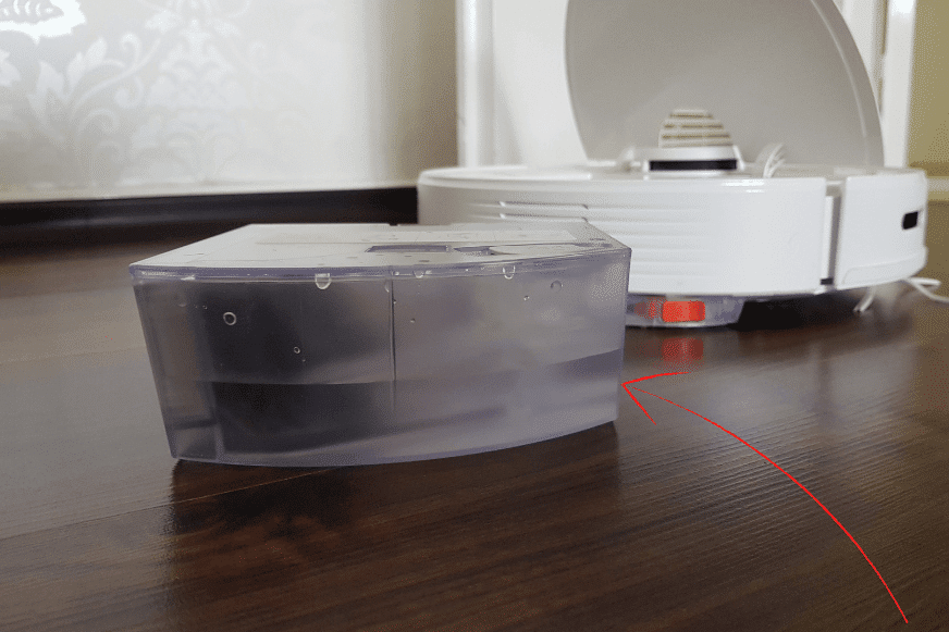 Резервуар для воды с остатками воды находится на полу за Roborock Q7 Max